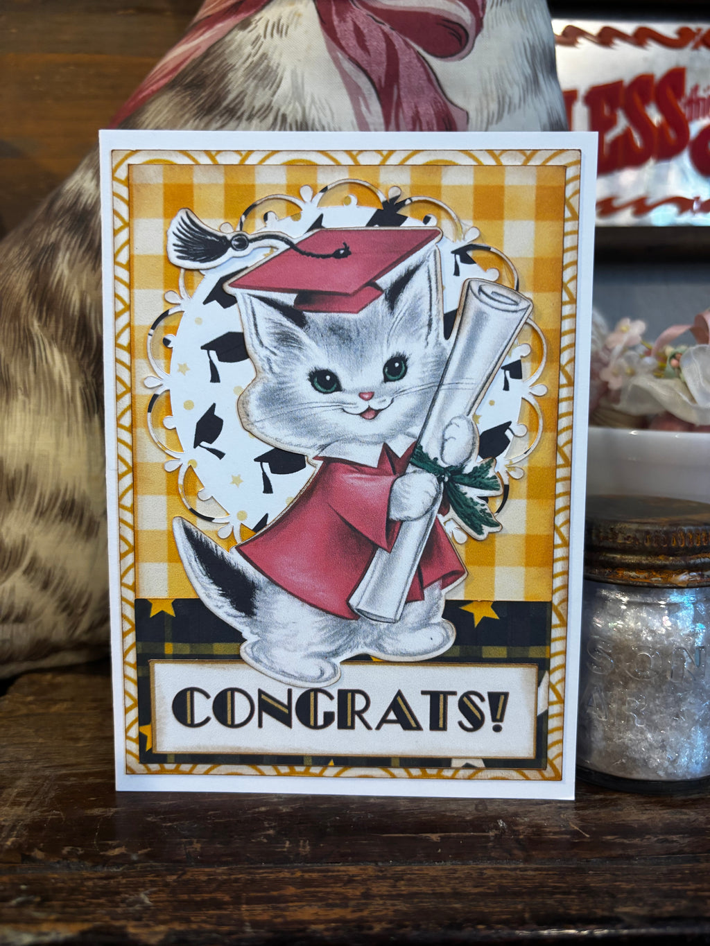 Graduation-themed card with a vintage cat in a redish cap and gown holding a diploma.