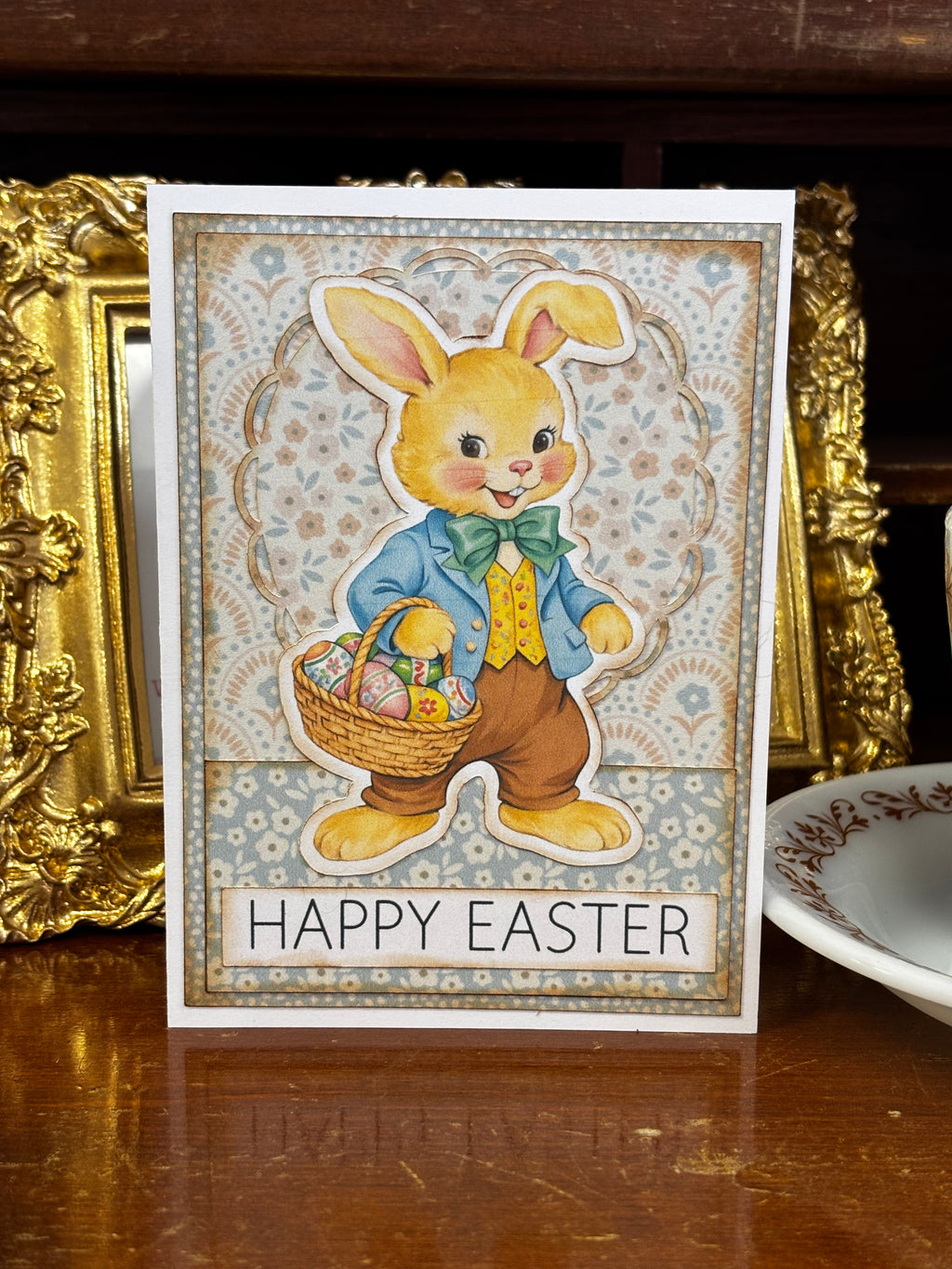 Vintage-style Easter card with a bunny holding a basket of eggs on a wooden surface.