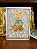 Vintage-style Easter card with a bunny holding a basket of eggs on a wooden surface.
