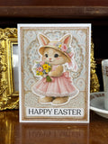 Easter card with a bunny in a dress and bonnet holding flowers with the text "Happy Easter"
