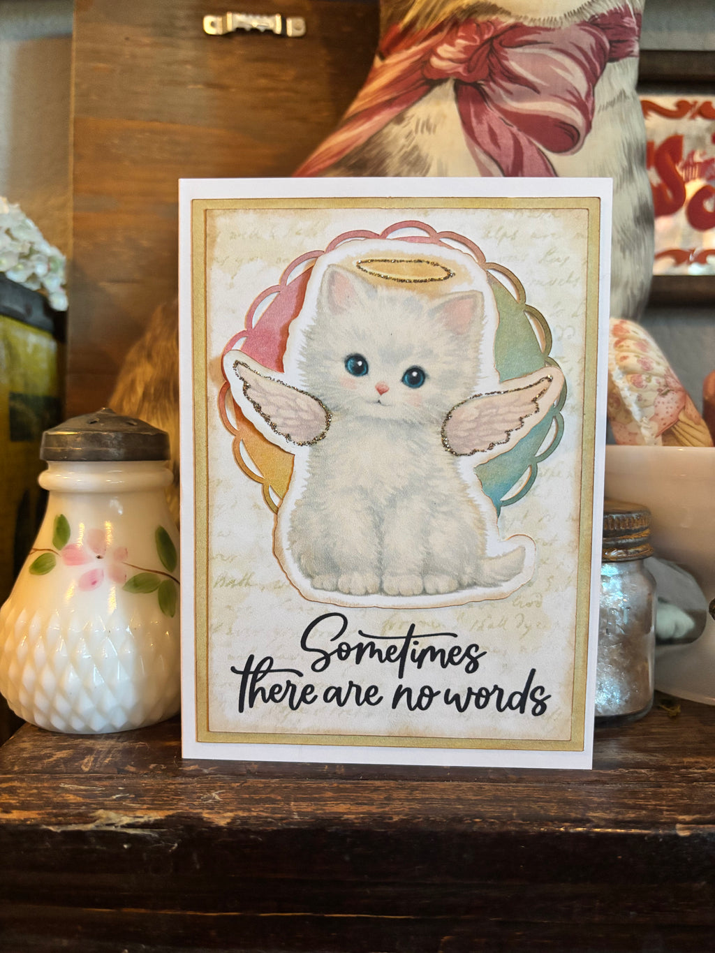 Memorial card with a cat with angel wings and a halo illustration, and the text 'Sometimes there are no words'. 