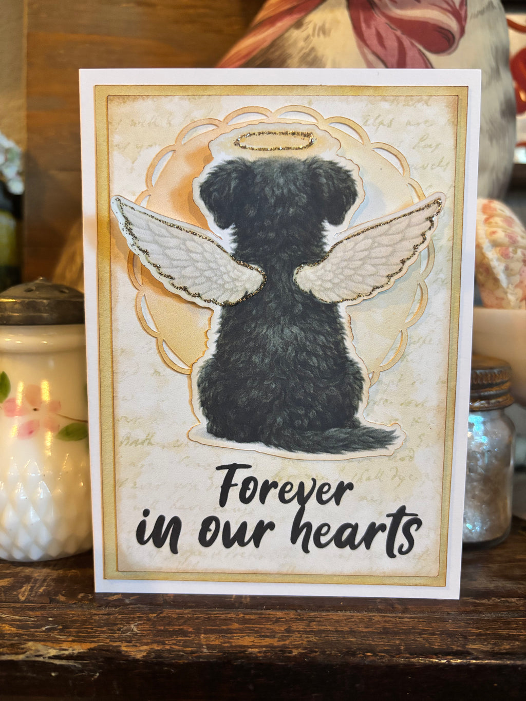 Memorial card with a dog with angel wings and a halo illustration and the text 'Forever in our hearts'. 