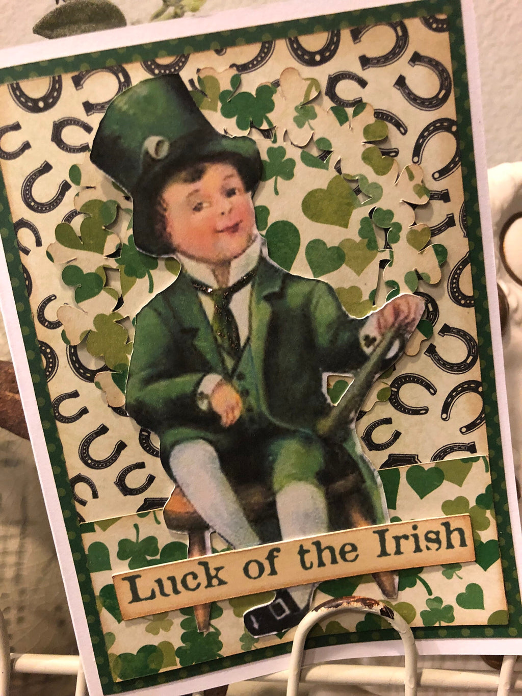St. Patrick's Day card with a boy in a green suit and top hat, surrounded by shamrocks and horseshoes, with 'Luck of the Irish' text.