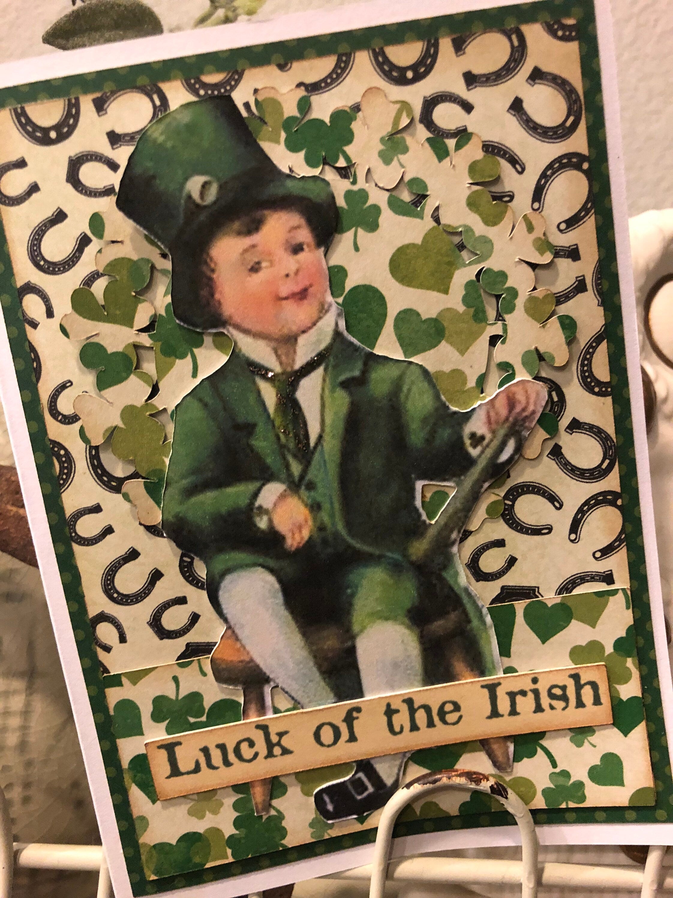 St. Patrick's Day card with a boy in a green suit and top hat, surrounded by shamrocks and horseshoes, with 'Luck of the Irish' text.